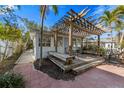 Outdoor deck with a wooden pergola, seating area, and landscaped surroundings at 520 Spring Ave # A, Anna Maria, FL 34216