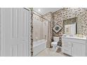 A well-lit bathroom with geometric patterned wallpaper, a tub, and a modern vanity with white cabinets at 5628 Summit Point Cir # 103, Bradenton, FL 34210