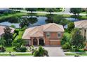 Aerial view of a charming two-story home with a tile roof, surrounded by lush greenery and a serene pond at 6961 Scrub Jay Dr, Sarasota, FL 34241