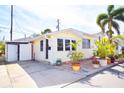 Charming yellow home featuring an open carport, tropical plants, and an inviting brick patio at 7 High St, Bradenton, FL 34208