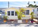 Charming yellow home with white trim surrounded by tropical plants and a brick patio at 7 High St, Bradenton, FL 34208