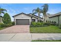 Inviting one-story home with a brick driveway, mature palm trees, and lush green lawn at 11050 Sandhill Preserve Dr, Sarasota, FL 34238