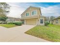 Two-story tan home featuring a well-manicured lawn, and a two-car garage at 11411 Flora Springs Dr, Riverview, FL 33579