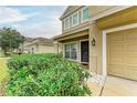 Tan home featuring a well-manicured lawn, front porch, and a two-car garage at 11411 Flora Springs Dr, Riverview, FL 33579
