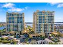 Exterior view of two condo buildings with palm trees and a parking area in the surrounding landscape at 130 Riviera Dunes Way # 1201, Palmetto, FL 34221