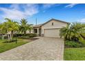 Charming single-story home features a paver driveway, two-car garage, and tropical landscaping under a blue sky at 17234 Blue Ridge Pl, Bradenton, FL 34211