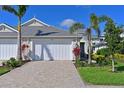 Villa with a two-car garage, brick paved driveway and tropical landscaping at 209 Okeeffe Cir, Bradenton, FL 34212