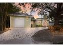 Inviting single-story home with a detached garage, gravel driveway, and landscaped front yard at dusk at 3521 Almeria Ave, Sarasota, FL 34239