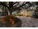 Charming single-story home with a red front door, manicured landscaping and a large tree in the front yard at 3521 Almeria Ave, Sarasota, FL 34239