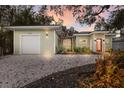 Inviting single-story home with a detached garage, gravel driveway, and landscaped front yard at dusk at 3521 Almeria Ave, Sarasota, FL 34239