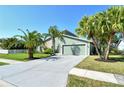 Home showcasing a well-maintained lawn, mature palm trees, and a long concrete driveway at 4712 Glenbrooke Dr, Sarasota, FL 34243