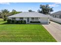 Charming single-story home featuring a well-maintained lawn, manicured shrubs, and a classic white exterior at 6320 Tilly St, Englewood, FL 34224