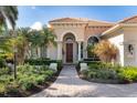 Inviting front entrance featuring an arched doorway, elegant columns, and meticulously maintained landscaping at 7141 Whitemarsh Cir, Lakewood Ranch, FL 34202