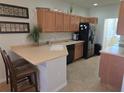 Kitchen featuring tan counters, wood cabinets and black appliances, complete with breakfast bar seating at 3780 82Nd Avenue E Cir # 101, Sarasota, FL 34243