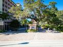 Gated community entrance with mature trees, Spanish moss and lush tropical landscaping at 5591 Cannes Cir # 403, Sarasota, FL 34231