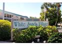 The White Sands Village community sign is surrounded by lush foliage and is a welcoming sight at 5665 Midnight Pass Rd # 410, Sarasota, FL 34242