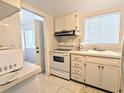 A compact kitchen featuring white cabinetry, essential appliances and a window for natural light at 5904 Palm Ln # C23, Bradenton, FL 34207