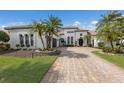 A picturesque home exterior featuring a brick driveway, manicured lawn, and mature palm trees at 7210 Desert Ridge Gln, Lakewood Ranch, FL 34202
