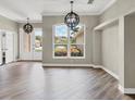 Open-concept living space with elegant lighting, gray walls, wood floors, and views of the landscaped exterior at 7723 Heyward Cir, University Park, FL 34201