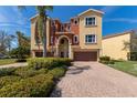 Charming multi-story home with a red-brick driveway, lush landscaping, and a two-car garage at 1318 3Rd Street E Cir, Palmetto, FL 34221