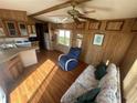 Cozy living room featuring wood paneling, a ceiling fan, and comfortable seating arrangement, ideal for relaxation at 3333 26Th E Ave # 1025, Bradenton, FL 34208