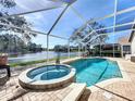 Inviting screened-in pool area featuring a spa, set against a serene lake view at 5242 Highbury Cir, Sarasota, FL 34238