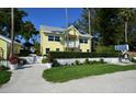 Charming yellow beach resort features a white picket fence and lush landscaping at 5581 Gulf Of Mexico Dr, Longboat Key, FL 34228