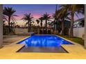 Backyard oasis with a crystal blue pool, stone pavers, lush landscaping, and lounge chairs at 108 Magnolia Ave, Anna Maria, FL 34216