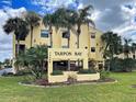 Well-manicured lawn with palm trees and sign reading Tarpon Bay at 14459 River Beach Dr # 218, Port Charlotte, FL 33953