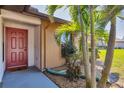 Close-up of the home's entrance featuring a striking red door and vibrant tropical foliage at 1709 Curry Trl # 30, Nokomis, FL 34275