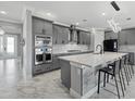 Modern kitchen with gray cabinets, stainless steel appliances, a large island, and granite countertops at 17814 Cresswind Ter, Bradenton, FL 34211