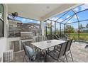 Covered outdoor kitchen featuring stainless steel appliances, a granite countertop, and an outdoor dining area at 17814 Cresswind Ter, Bradenton, FL 34211