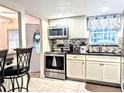 View of kitchen featuring stainless steel appliances, white cabinetry, tile backsplash, and granite countertops at 2057 Sunset Dr # G1, Bradenton, FL 34207