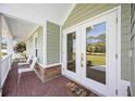 Inviting front porch with brick flooring, rocking chairs and double glass doors at 3595 Shamrock Dr, Venice, FL 34293