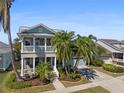 Charming two-story coastal home with a covered front porch, a second-story balcony, mature palm trees, and an attached two-car garage at 428 Islebay Dr, Apollo Beach, FL 33572