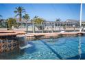 Inviting pool with waterfall feature and in-water seating, set against a backdrop of waterfront homes at 428 Islebay Dr, Apollo Beach, FL 33572