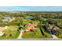 Stunning aerial view of the house with a large yard, mature trees, a pond and picturesque golf course views at 6107 Glen Abbey Ln, Bradenton, FL 34202