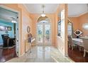 Elegant foyer featuring marble floors, decorative glass doors, and views into the dining and office areas at 6107 Glen Abbey Ln, Bradenton, FL 34202