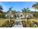 Beautiful single-story home with symmetrical palm trees lining the paver driveway and lush landscaping at 8455 Lindrick Ln, Bradenton, FL 34202