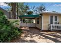 View of a yellow house with a brick driveway and a green awning over a gate at 980 S Orange Ave, Sarasota, FL 34236