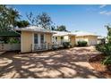 Quaint yellow home with a brick driveway, a small porch, and lush landscaping at 980 S Orange Ave, Sarasota, FL 34236