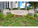 Beautifully landscaped entrance sign for Sunset Towers, surrounded by lush greenery and mature trees at 11 Sunset Dr # 303, Sarasota, FL 34236