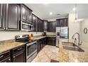 Gourmet kitchen featuring dark wood cabinetry, stainless steel appliances, and granite countertops at 16612 Myrtle Sand Dr, Wimauma, FL 33598