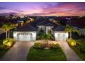 Elegant home exterior showcasing a three-car garage and a beautifully landscaped yard at dusk at 1805 7Th St E, Palmetto, FL 34221