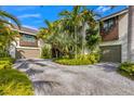 Home featuring a circular driveway leading to multiple garages surrounded by lush tropical plants at 212 Haverkos Ct, Holmes Beach, FL 34217