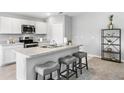 Modern kitchen island with bar stool seating, stainless steel appliances, and neutral gray countertops at 22368 Blanchard Ave, Port Charlotte, FL 33952