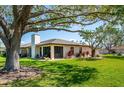 Spacious backyard with lush green grass, a covered patio, and mature trees providing ample shade at 3641 Gleneagle Dr # 12D, Sarasota, FL 34238