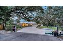 Gated driveway leading to a well-maintained home with a metal roof and manicured landscaping at 4045 Lisbon Pl, Sarasota, FL 34231
