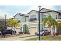 Attractive townhome showcasing light green exterior paint, a two-car garage, and tropical palm trees at 5118 78Th St E Cir, Bradenton, FL 34203
