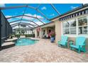 Inviting screened-in pool area with a beautiful brick patio, comfortable seating, and lush tropical plants at 5608 Tidewater Preserve Blvd, Bradenton, FL 34208